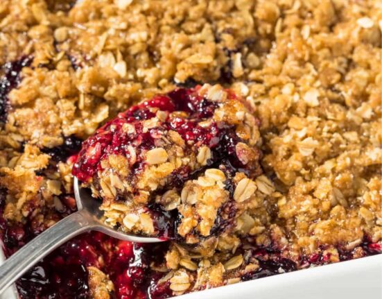 Blackberry Crisp in a white pan with a spoon in it