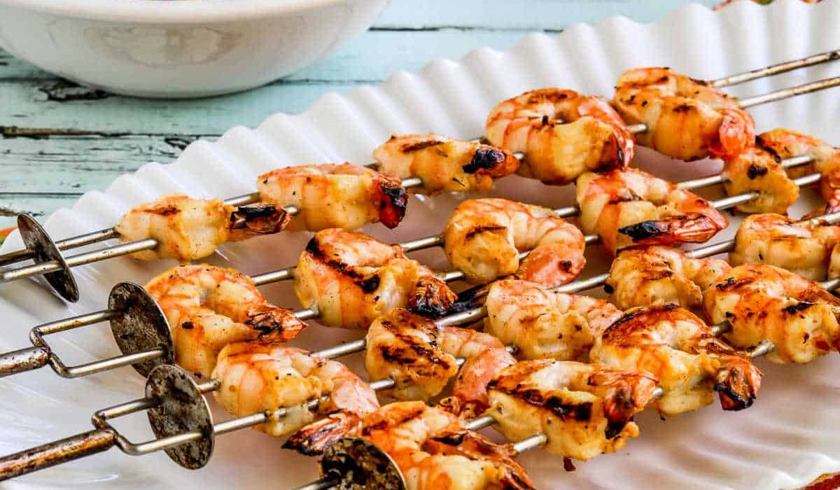 Square image of Grilled Shrimp Skewers on serving platter with black bean salsa in back.