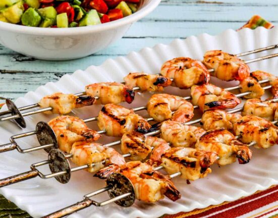 Square image of Grilled Shrimp Skewers on serving platter with black bean salsa in back.