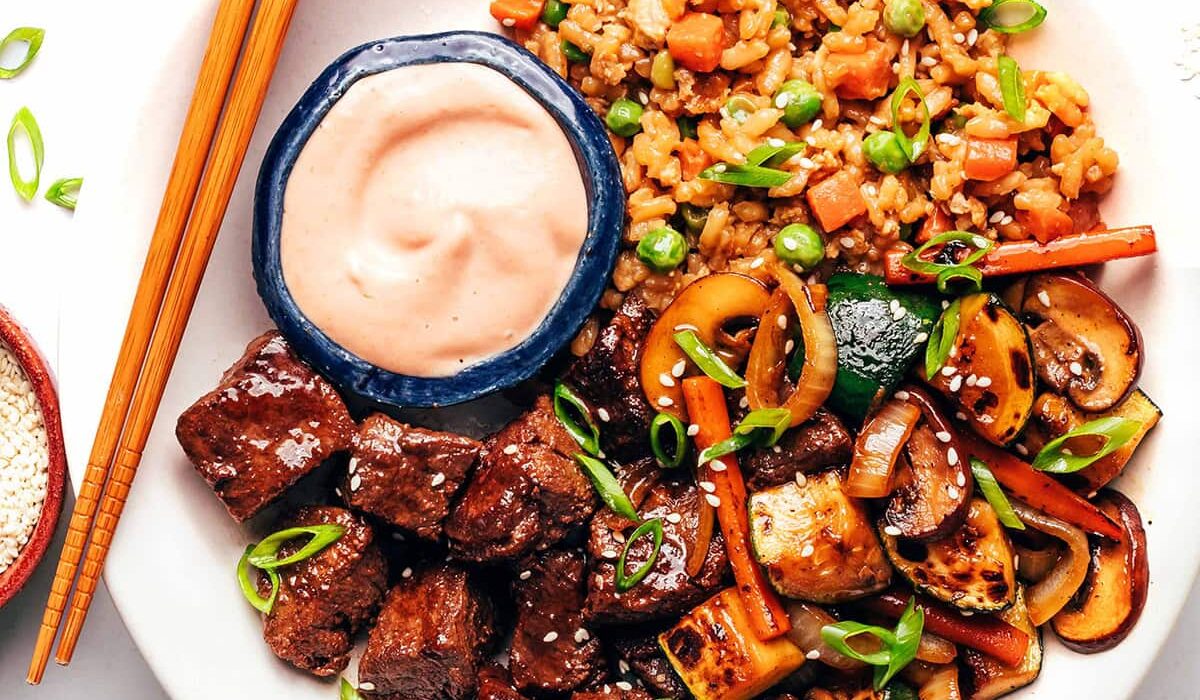 Hibachi steak on a plate with rice and veggies.