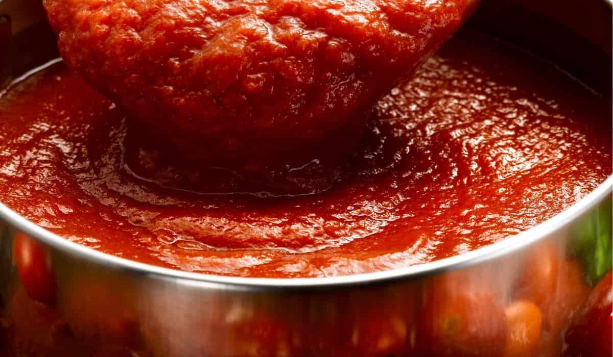 Homemade Pizza Sauce in a bowl being served with a spoon