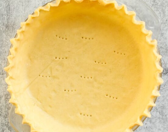 Overhead view of a gluten-free pie crust in a pie plate with fluted edges.