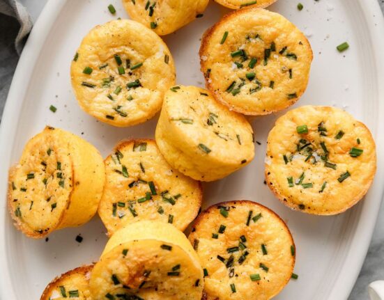 Close up view of a plate of egg bites topped with fresh chives and flakey sea salt.