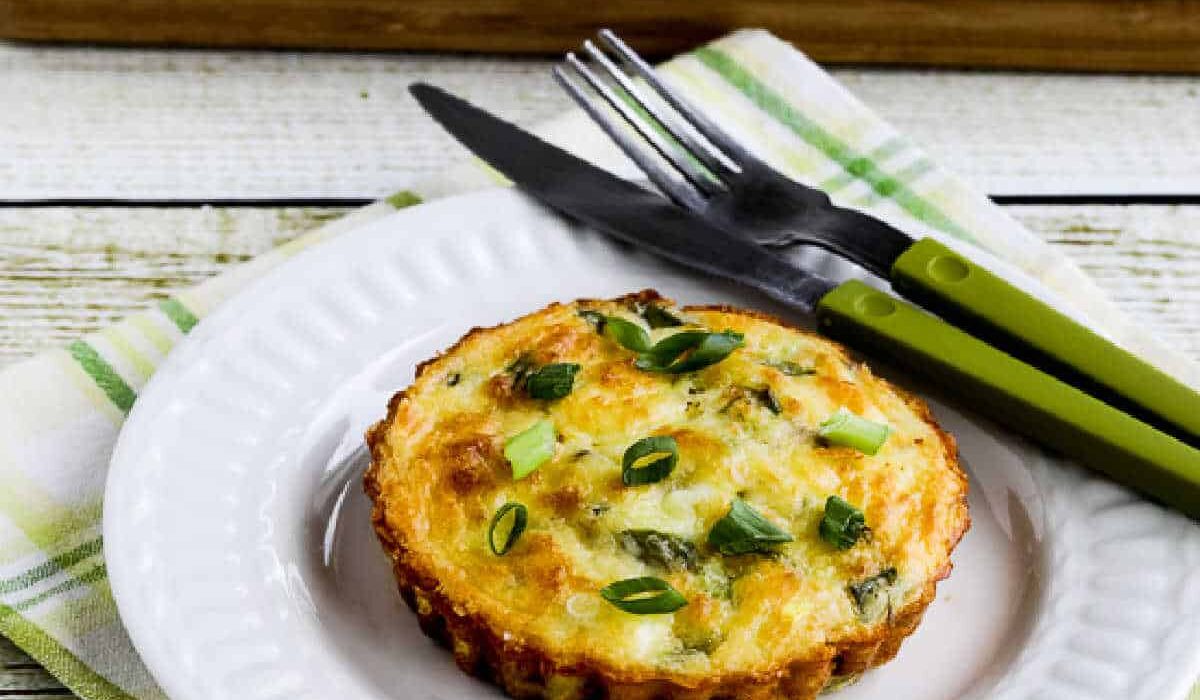 square image of Asparagus Breakfast Tarts with one on plate and tart pan in back
