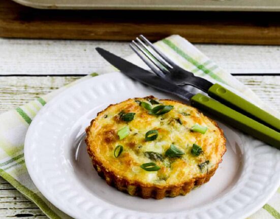 square image of Asparagus Breakfast Tarts with one on plate and tart pan in back