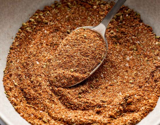 Close up view of a ceramic bowl filled with Homemade Taco Seasoning and a spoon in the bowl.