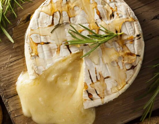 Overhead image of Baked Brie with a slice cut out of it on a cutting board