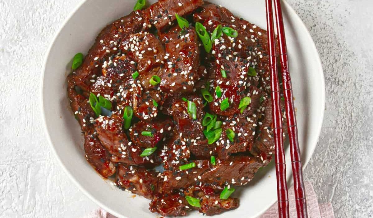 Overhead image of crispy beef in a white bowl with chopsticks
