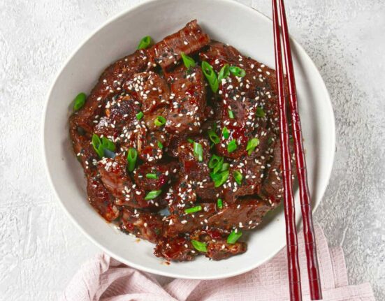 Overhead image of crispy beef in a white bowl with chopsticks