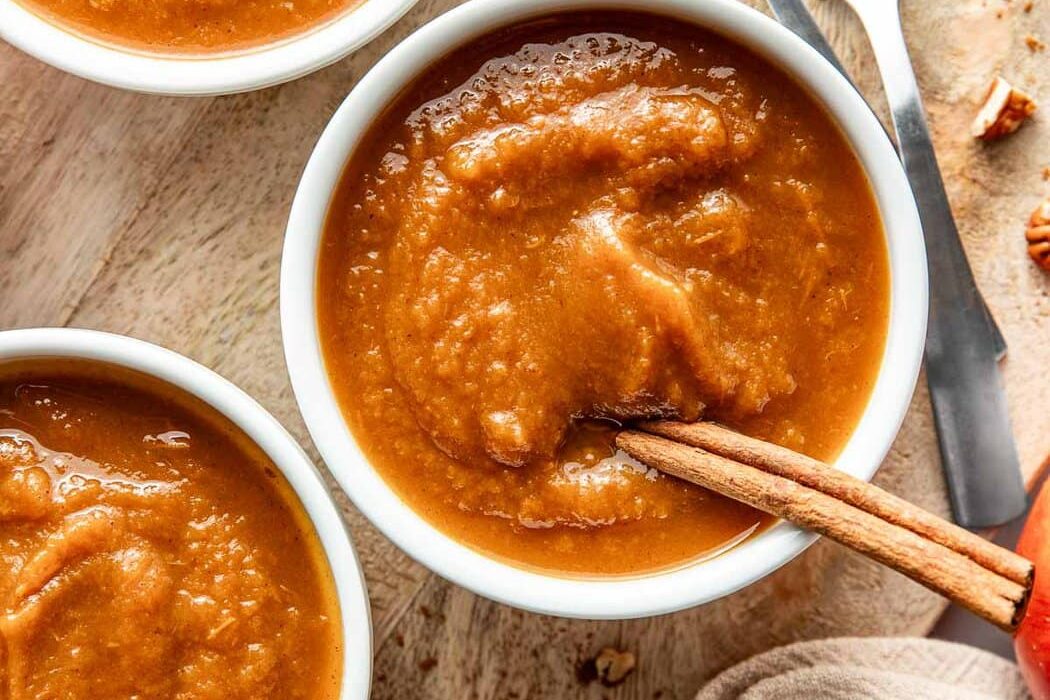 Overhead view of two small bowls of fresh crockpot pumpkin applesauce.