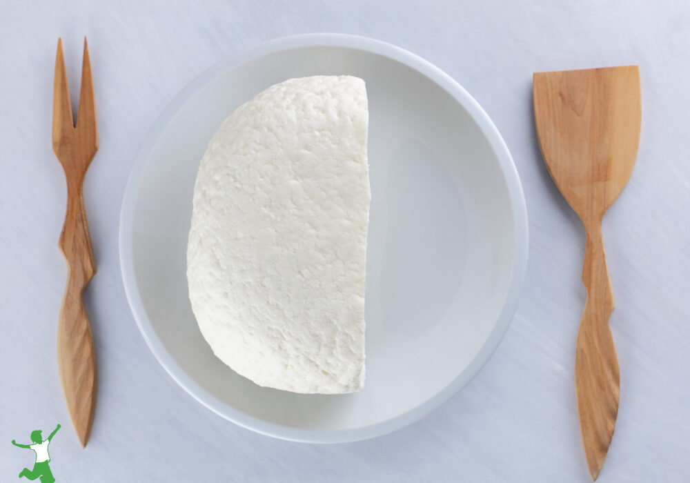 homemade kefir cheese on white plate with wood utensils