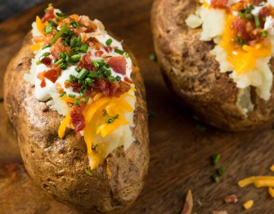 Two Jacket Potatoes with toppings on a wooden cutting board