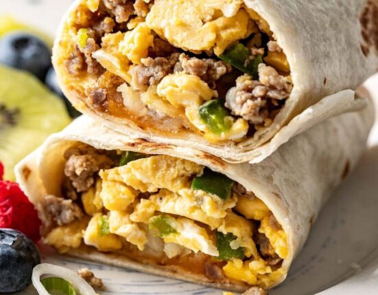 Close up view of a breakfast burrito cut in half and stacked showing the egg and sausage mixture on the inside.