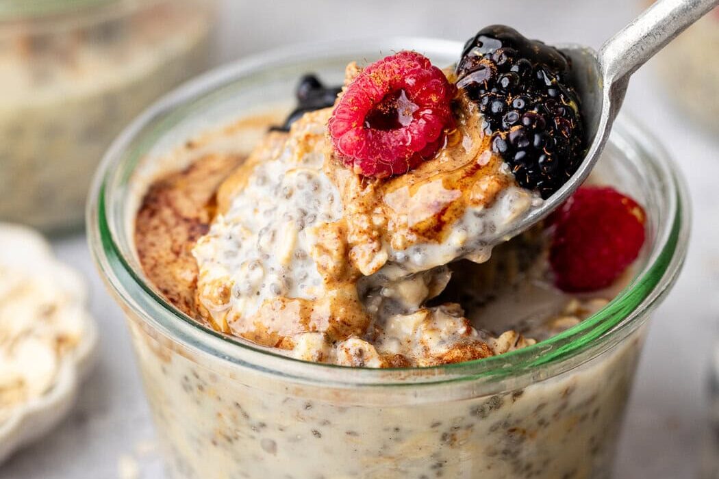 Close up view of a glass jar filled with Protein Overnight Oats topped with fresh berries and honey.