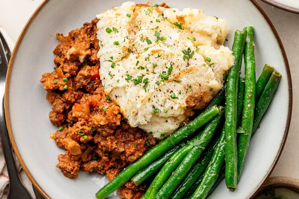 Overhead view of a plate of Sloppy Joe Casserole with green beans on the side.