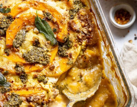 A serving spoon in a butternut squash gnocchi casserole dish.