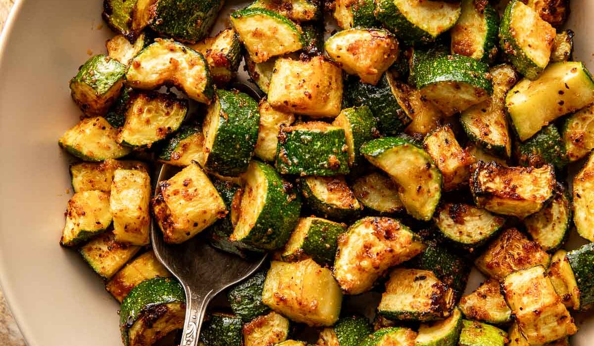 Overhead view of a ceramic bowl filled with Air Fryer Zucchini pieces with crisp texture.