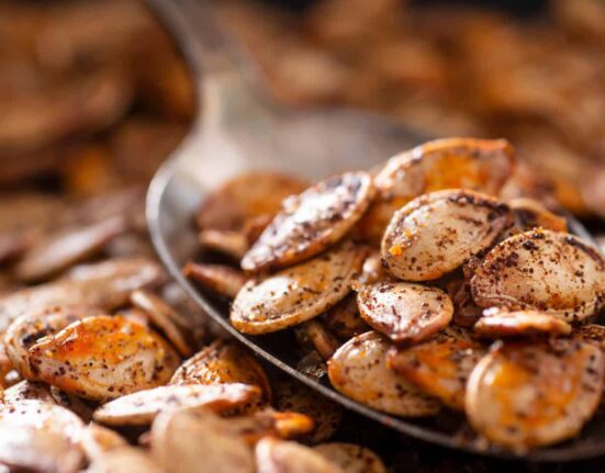 Roasted Pumpkin seeds on a spoon with more scattered under it