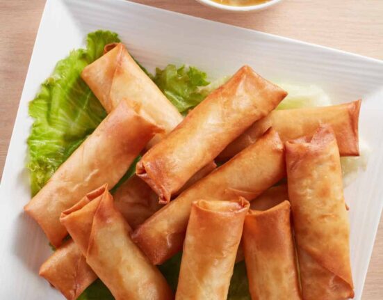 Overhead image of air fryer spring rolls on a white square palte