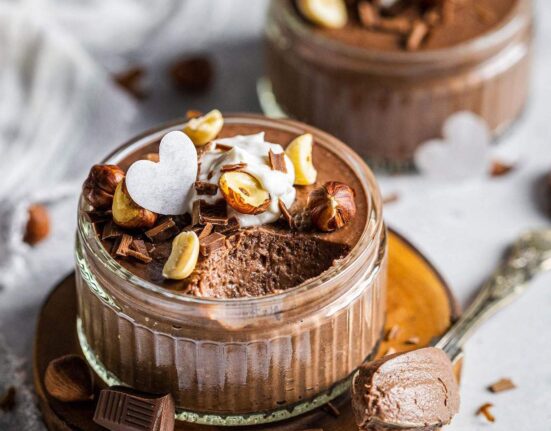 Creamy chocolate mousse in a ramekin with a spoon next to it.