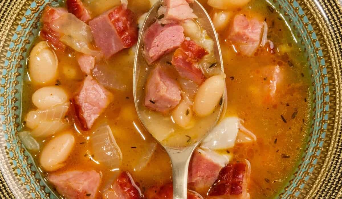 Overhead image of slow cooker ham and beans in a bowl with a spoon