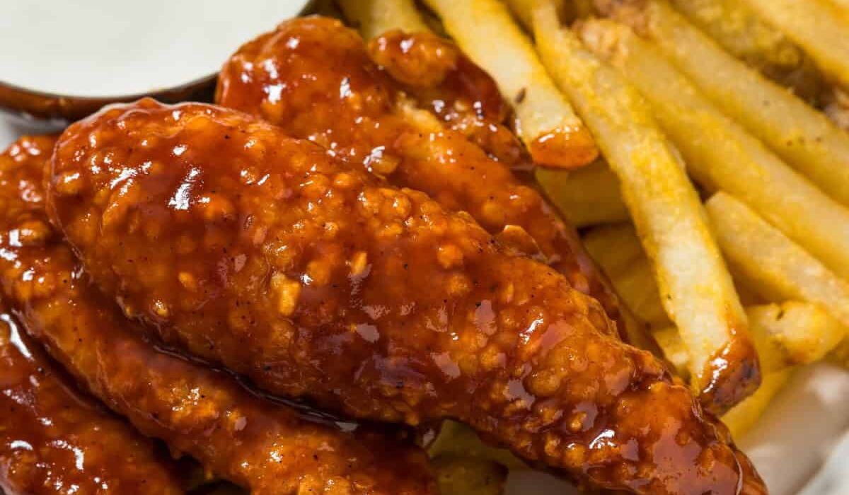 Close up image of Honey BBQ Chicken Tenders on a plate with fries and ranch dressing