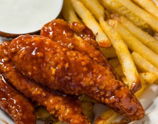 Close up image of Honey BBQ Chicken Tenders on a plate with fries and ranch dressing