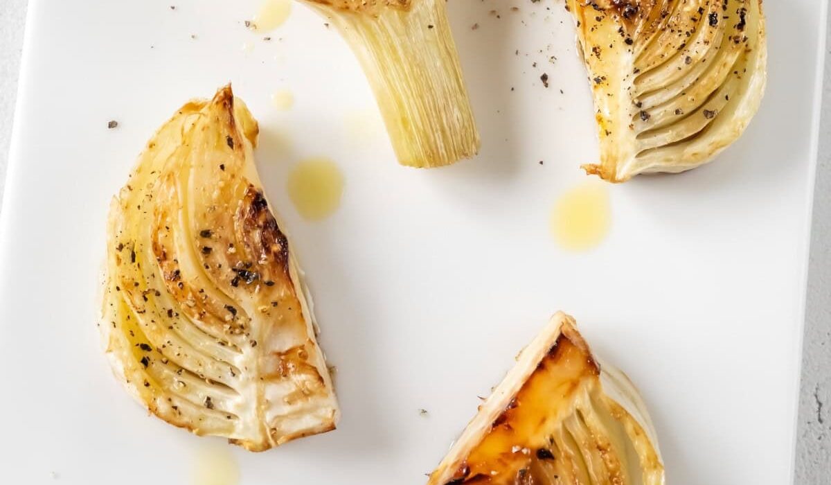 Overhead image of roasted fennel on a white serving tray