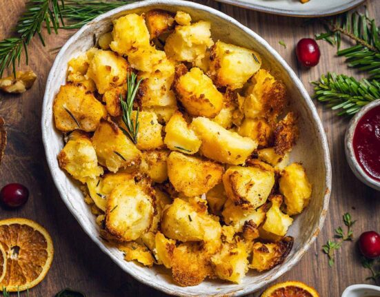 Vegan Roast potatoes in a serving dish on the dinner table.