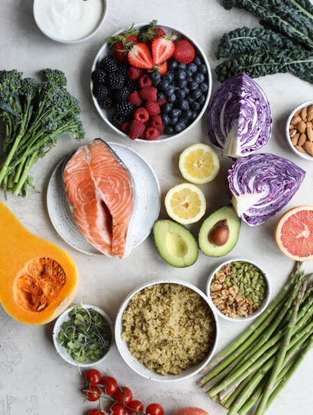 Overhead view of a variety of fruits, vegetables, and salmon on a marble countertop.