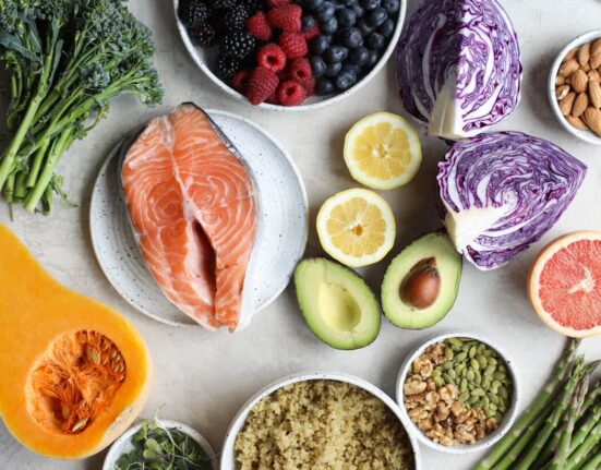 Overhead view of a variety of fruits, vegetables, and salmon on a marble countertop.