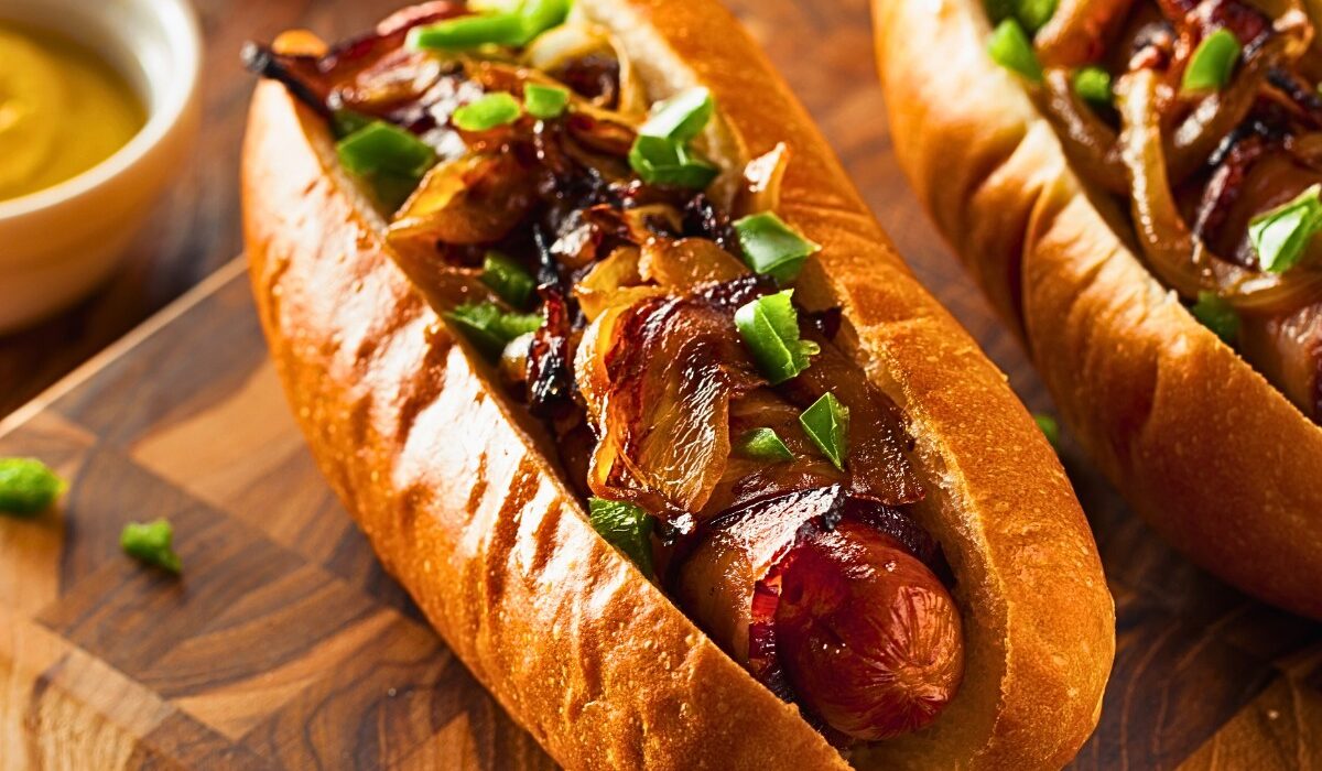 two air fryer bacon wrapped hot dogs on a wooden cutting board