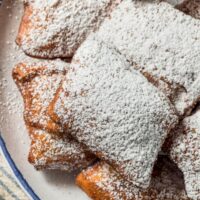 Overhead image of beignets dusted with powdered sugar on a plate