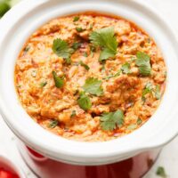 Close up view of a small slow cooker filled with Rotel Dip sprinkled with fresh cilantro.
