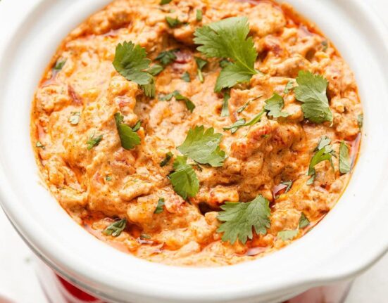 Close up view of a small slow cooker filled with Rotel Dip sprinkled with fresh cilantro.