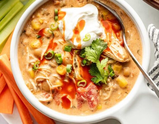 Overhead view of a bowl of Buffalo Chicken Chili topped with green onions and a dollop of sour cream