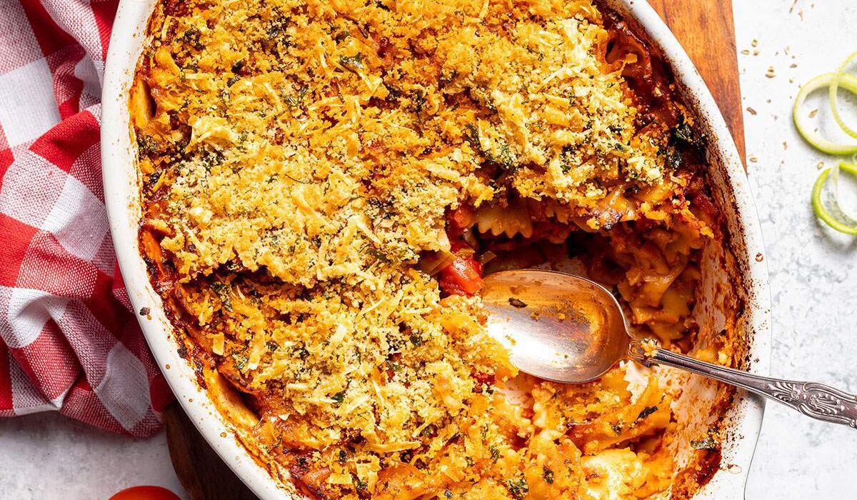 A casserole dish filled with vegan pasta bake and a serving spoon on the side.