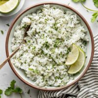Overhead view of a bowl of Cilantro Lime Rice garnished with lime wedges.