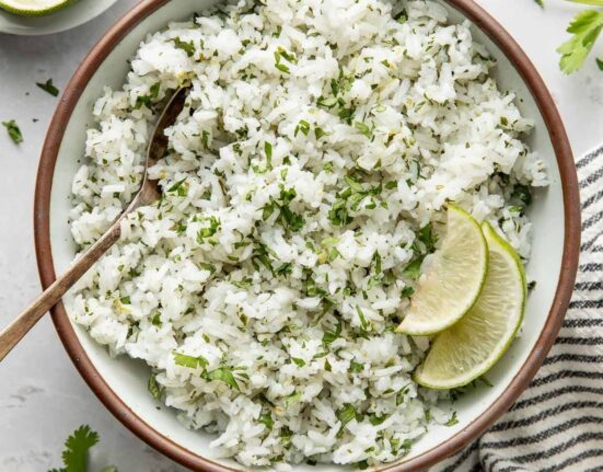 Overhead view of a bowl of Cilantro Lime Rice garnished with lime wedges.
