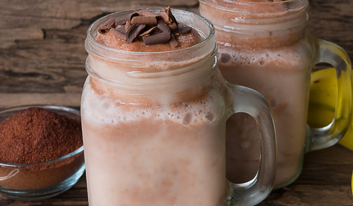 two coffee smoothies in mason jars on a wooden surface