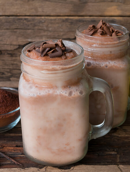 two coffee smoothies in mason jars on a wooden surface