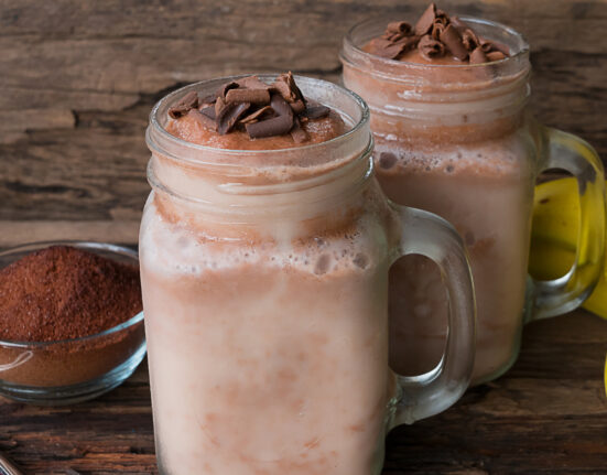 two coffee smoothies in mason jars on a wooden surface