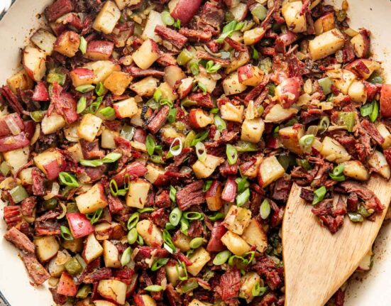 Overhead view of a white skillet filled with Corned Beef Hash topped with green onions.