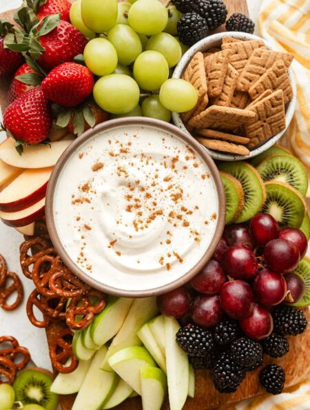 Overhead view of a variety of colorful fruit with a bowl of creamy fruit dip in the middle sprinkled with cinnamon.