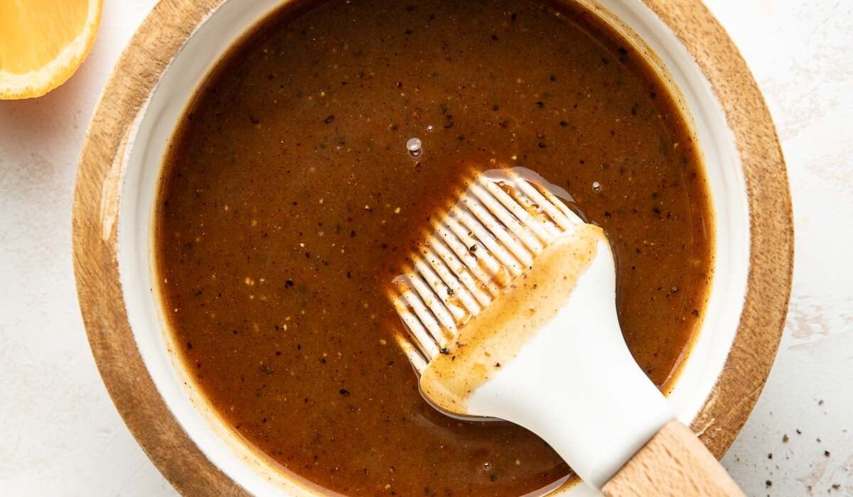 Overhead view of a small dish filled with Ham Glaze mixture next to sliced oranges.