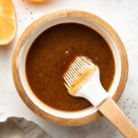 Overhead view of a small dish filled with Ham Glaze mixture next to sliced oranges.