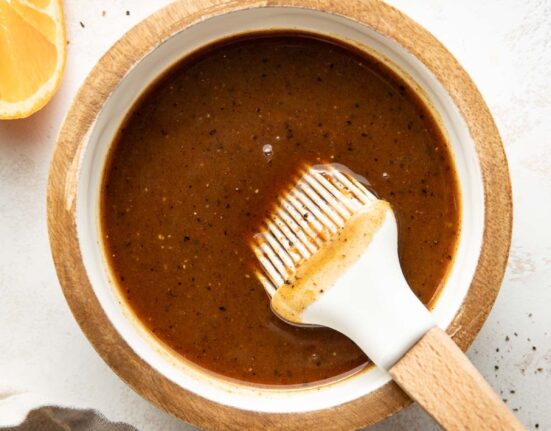 Overhead view of a small dish filled with Ham Glaze mixture next to sliced oranges.