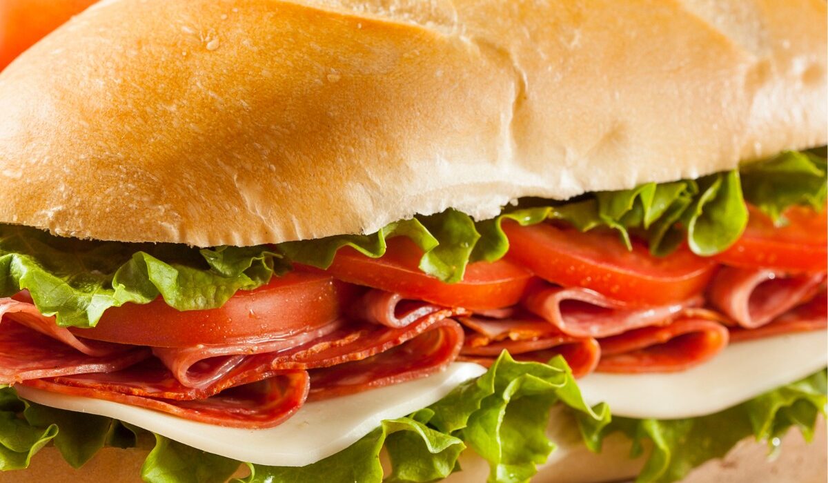 Two Italian Sub Sandwiches on a wooden cutting board