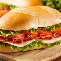 Two Italian Sub Sandwiches on a wooden cutting board