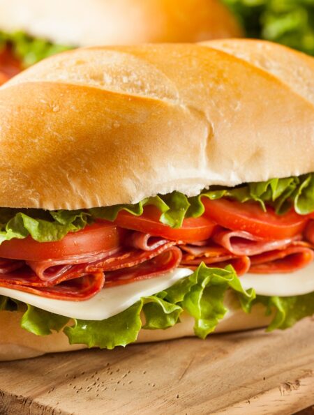 Two Italian Sub Sandwiches on a wooden cutting board